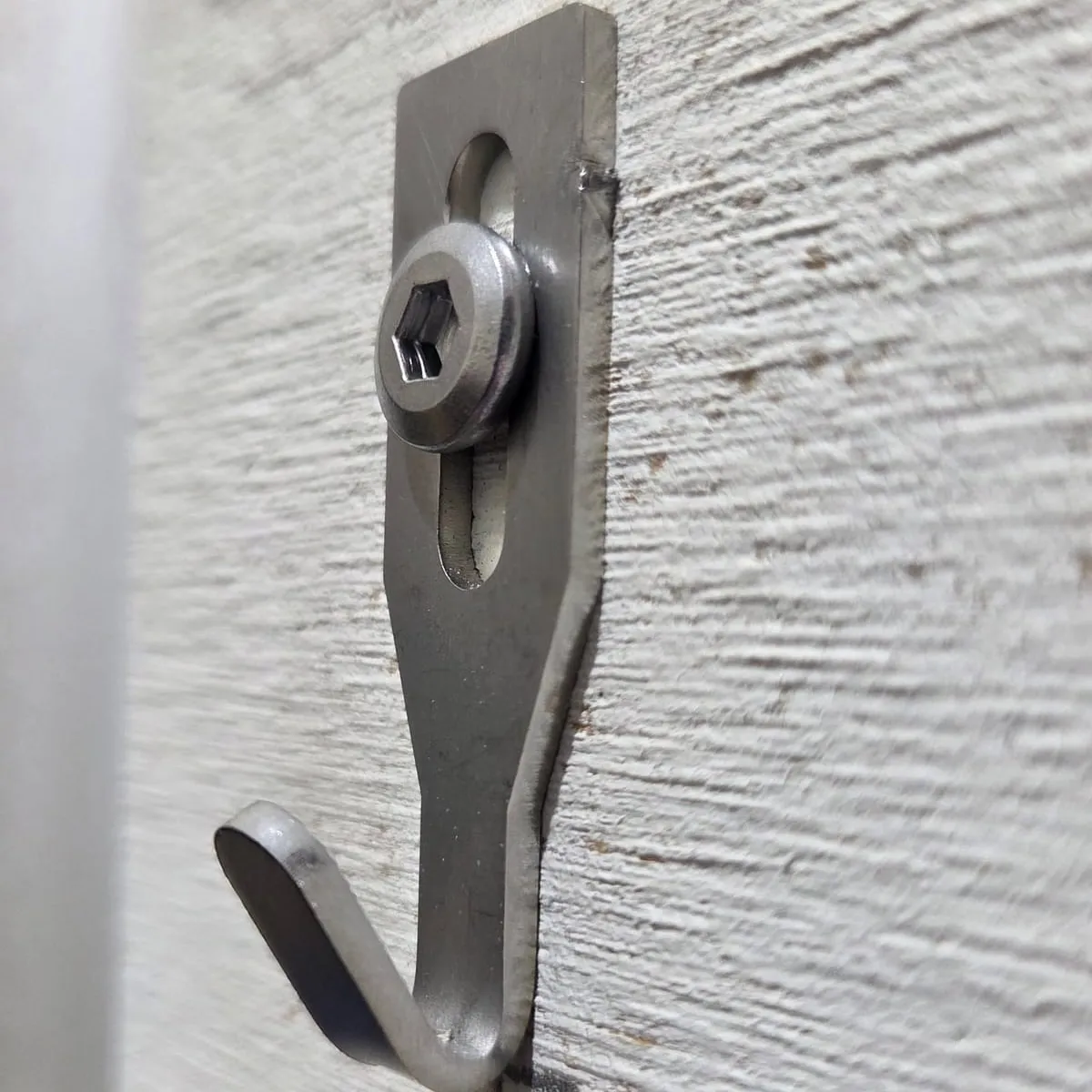 Centre Hook Small fixed to a textured painted wall with a stainless hex-socket screw, angled side view