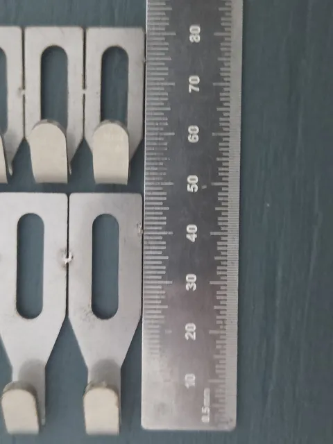 Stainless centre hooks laid out beside a steel rule